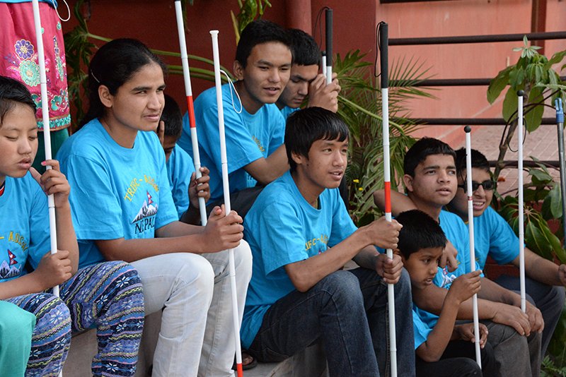 Children with visual impairments sitting together, each holding a white cane.