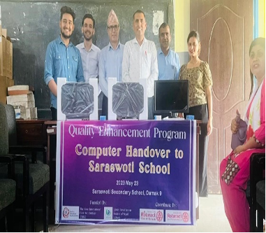Group photo holding a banner that reads"computer handover to saraswoti school"