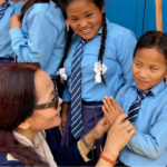 A visually impaired child greeting an Adson member with a namaste.